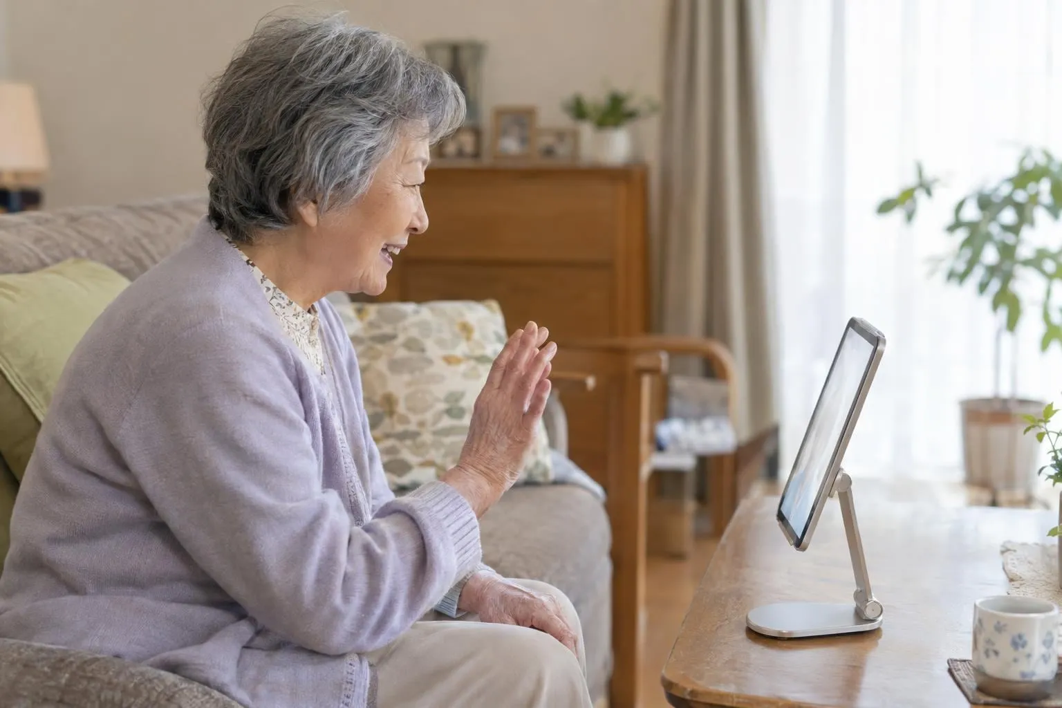 タブレットに話しかける高齢の女性