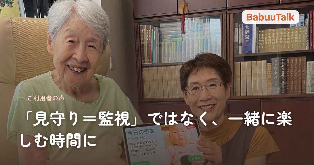 居間の椅子で、BabuuTalkの画面を映したタブレットをご家族と一緒に持って笑うお母様